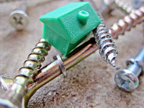 A little green house on top of some screws to symbolise building a brand that works for you