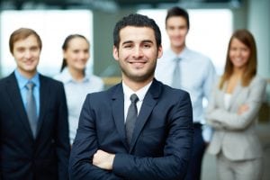 Grow your business from private to corporate takes time and courage. A man standing with his hands crossed dressed in a suit. 