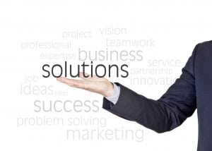 A hand holding the word solutions with blurred words in the background. There is always a solution for an at home business
