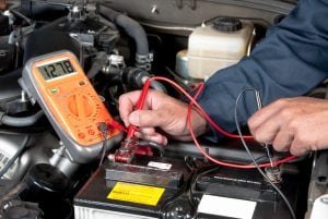 A mechanics hand measuring a battery. Opening your own mechanic shop or garage requires skills