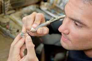 A person making a handmade jewlry to put in the shop window, marketing his own business. 