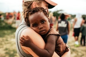 Photo of a baby in the arms of a charity worker. Marketing for charities is crucial to be able to get donations and fullfill helping people. 