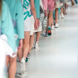 Lots of feet walking forward in a fashion show. Branding some clothes