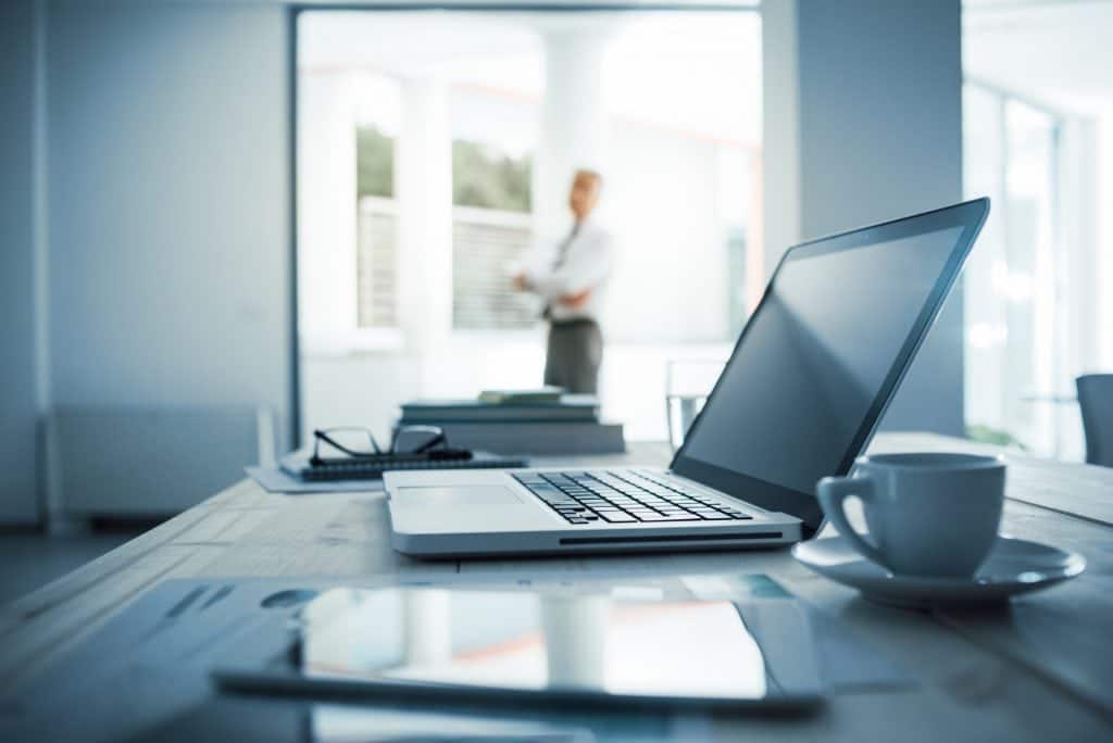 A government contracting business can be fun but it's serious business so be do what is expect of you. A computer on a desk with a man standing in the background