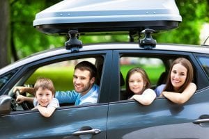 A family of four sitting in a car. Everybody needs car insurance companies to stay safe