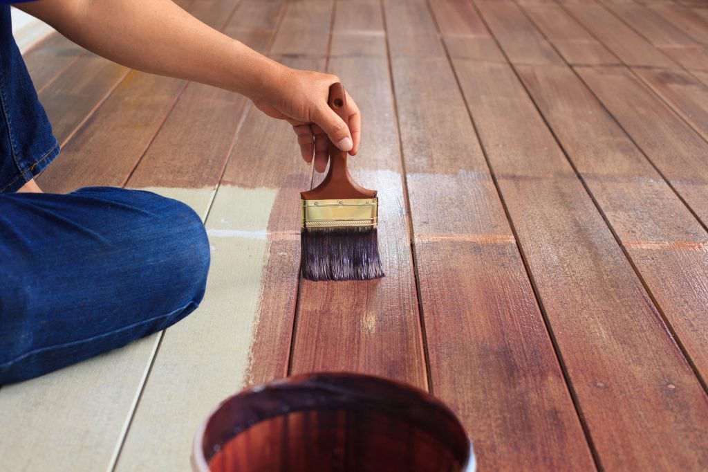 A hand putting floor oil on wood flooring. Starting your painting company needs clever branding and great reviews