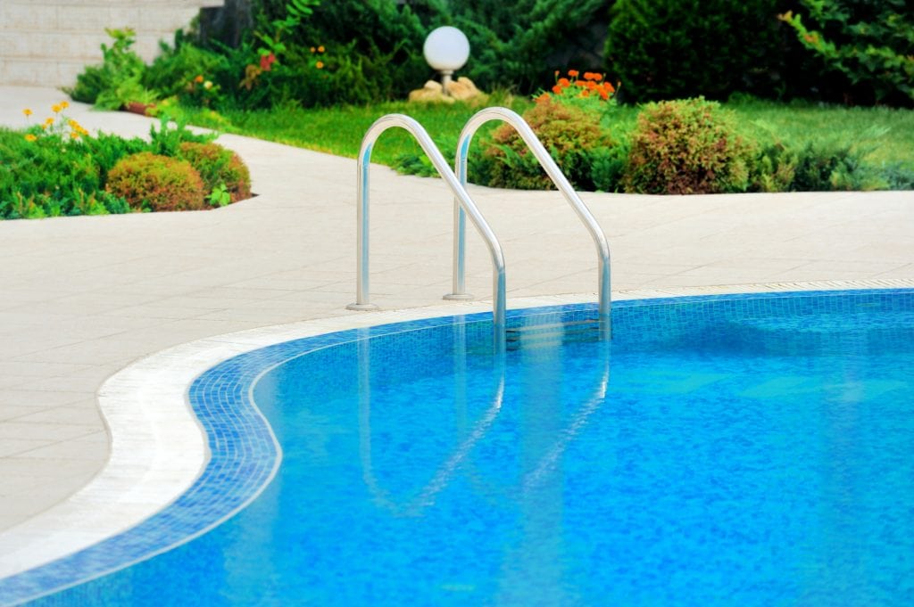 Pool ladder. Lovely gardens in the background. Making this a perfect picture for a pool and spa installation business 