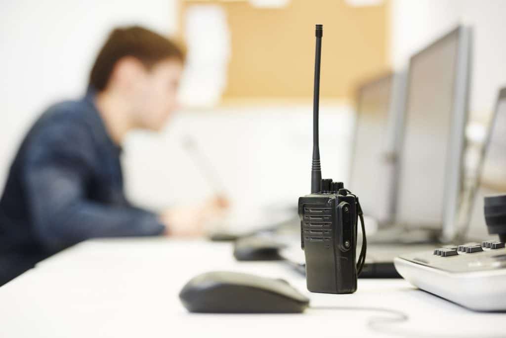 Radio with a man in the background working on a computer. Working at a Private security firm