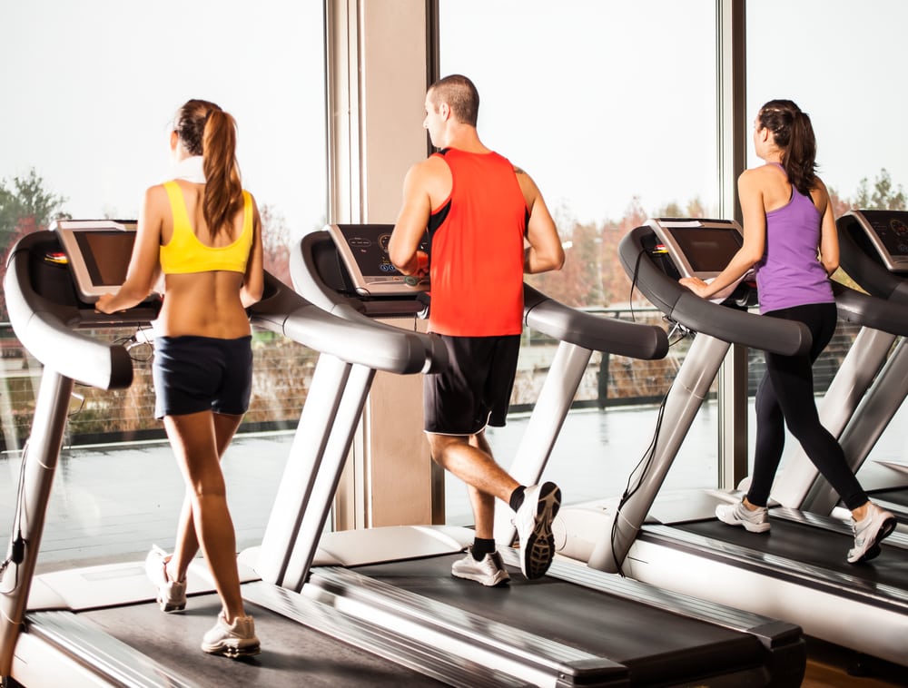 People running on the treadmills in colorful outfits. Planning an event to rebrand your gym involves showing your equipments