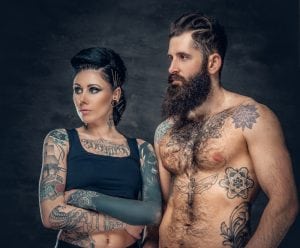 Two beautiful tattooed people looking to the left. Marketing tattoo parlors is crucial to have customers chose you as a business. 