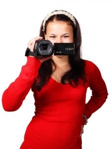 A woman in a red top holding a camera probably thinking of content marketing trends.