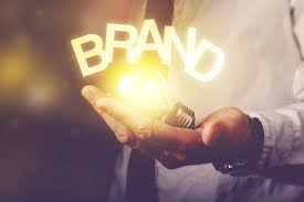 A hand is holding a light bulb with the words BRAND on top of it symbolising branding your business