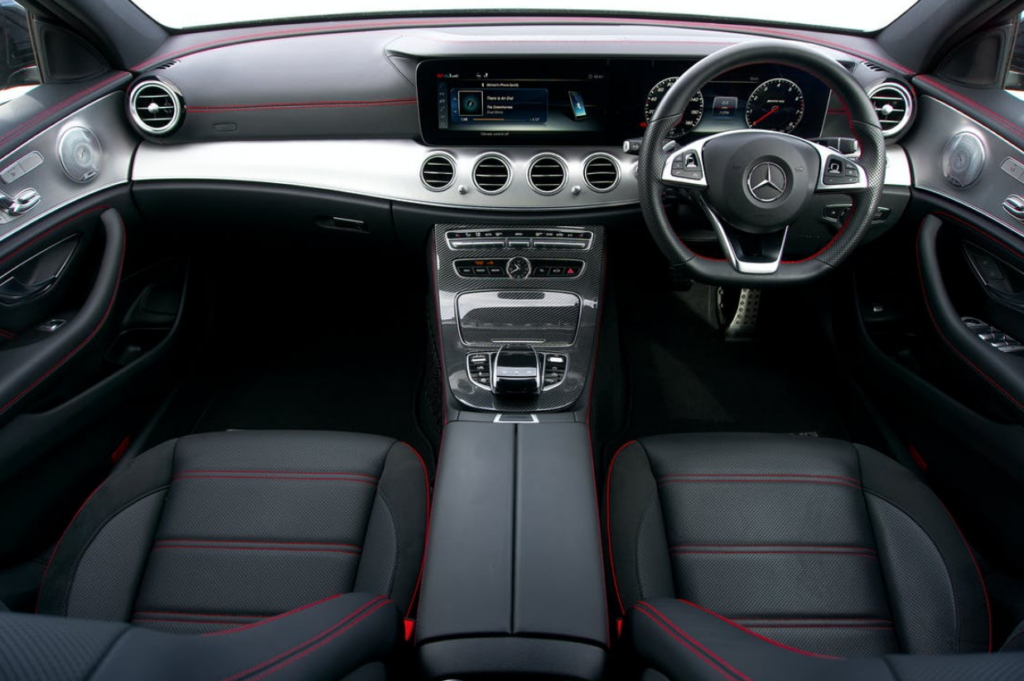 Inside of a Mercedes-Benz with the car logo on the steering wheel.