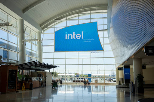 Intel logo on a blue background on a wall of windows in an airport. Latest logo trends followed by Intel