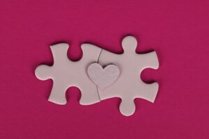 Pink puzzle bits fitting together with a pink heart on top. The difference between branding and marketing. 