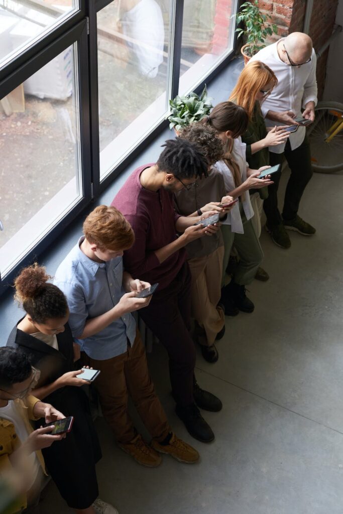 A row of people looking at their mobiles being obsessed with social media and how social media affects people