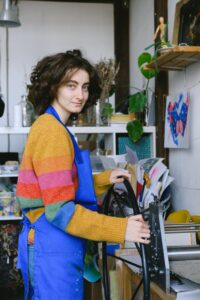 Woman holding papers in a colorful top thinking about how to brand and market her products.