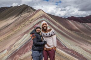 Two people holding each other on a colorful mountain top. This photo is perfect for a travel website