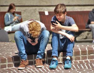 Two teenagers watching their mobil phones. Marketing to teens can be done via TikTok or Snapchat but you need to be careful and do it correctly. 
