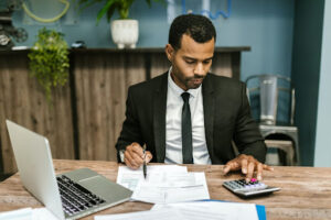 Accountant using a calculator in front of his laptop