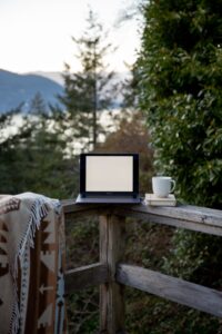 A computer standing on the edge of a fence in the garden. A cup of coffee to the right hand side. A typical outside office working day view at the office for me