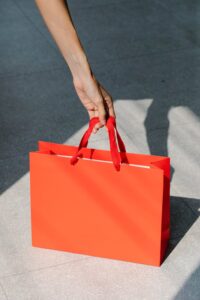 Orange gift bag on the ground. Picked up by a hand,