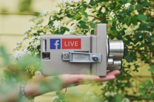 Old camera with a Facebook and LIVE logo that is hold by one hand