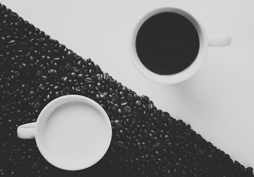 Two coffee cups each in black and white on the opposite color coordinated background