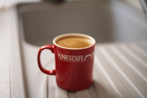A red coffee cup with the company name Nescafé in a perfect logo size