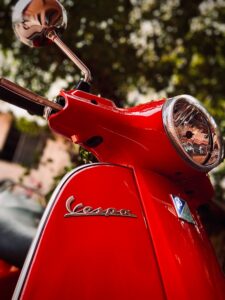 Vespa in red with the wordmark vs logo on either side of the bike.