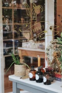Shop window with a vintage look. A green plant in the window. The text on the window says Aromatherapy. Brand name and trade names are different