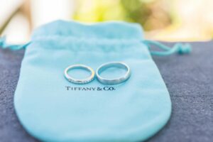 Tiffany & Co feminine logo design with 2 wedding rings on a little velvet blue bag.