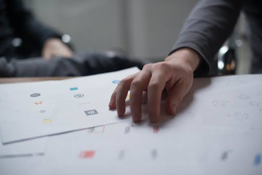 A hand on a desk with papers symbolising 10 fresh logo design ideas for your company.