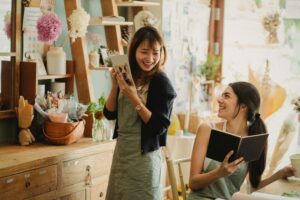 Cheerful women working together in floral shop. Logo design for AI-generated brands can be useful but never emotional