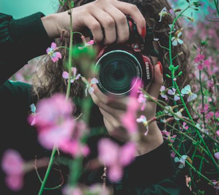 A woman taking a picure with a camera. Practising to add a picture to a logo