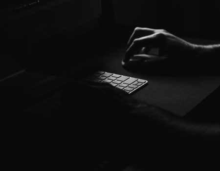 Conceptual Dark Image of Hands Typing on Keyboard. Symbolizing branding boosts