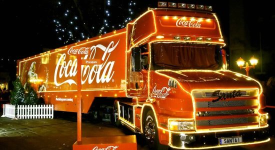 Coca Cola Christmas logo design on a red truck full of lights