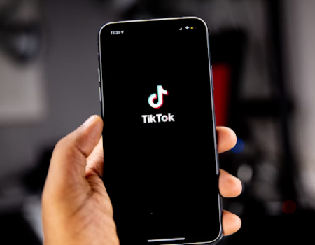 Hand holdimg a mobile with the app logo for TikTok