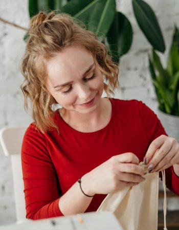 Woman Wearing Red Top sewing symbolizing the need for logo design for home-based business.