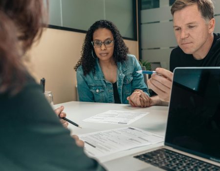 A Couple Listening to the Person Explaining Professional Logo Design Services and the Details of the Documents on the Table A Couple Listening to the Person Explaining Professional Logo Design Services and the Details of the Documents on the Table