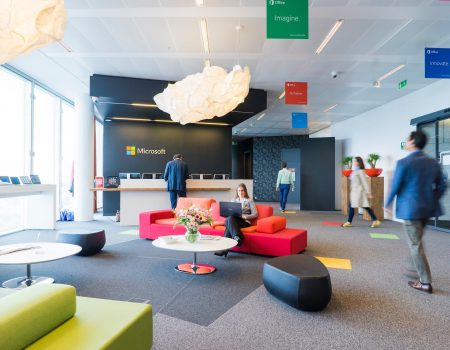 Beautiful office where you can see people coming into. One lady is sitting in a red sofa