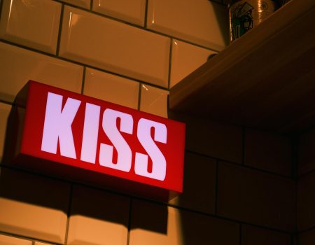 Photo of Kiss Signage on Wall. Examples of a red and white text logo design ideas