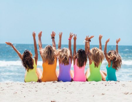 Girls sitting on a beach celebrating summer. Summer logos usually have fun graphics