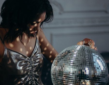 Woman holding mirror ball to show the sparkling silver effects on her dress