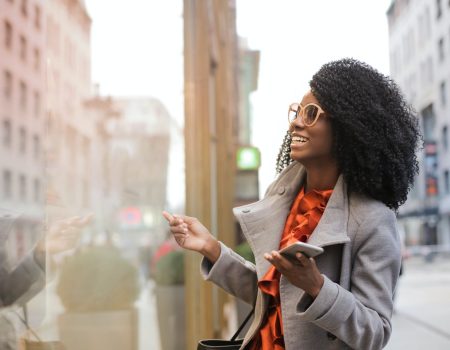 A woman looking happily into a glass window.