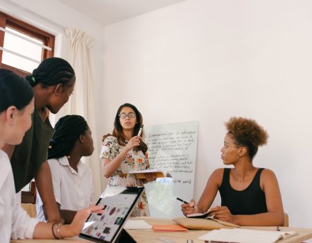 5 people in an office brainstorming for a new memorable brand name. Writing different ideas on a memory board