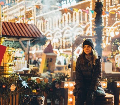 Holiday marketing for any business required strategies. A woman sitting on a bench surrounded buy lights at the Christmas market