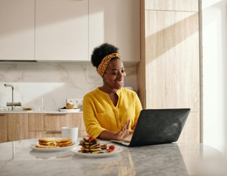 Happy Woman in Yellow Top Using a Laptop reading about email design ideas