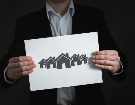 A guy holding a real estate logo design ideas in the shape of a sign