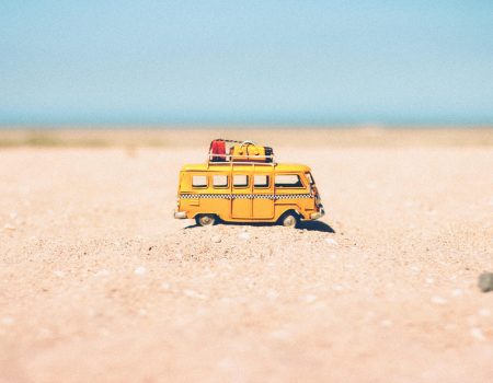 Image of a yellow camper van in the middle of the desert. Out travelling. Imagine a nice travel logo design on the car.